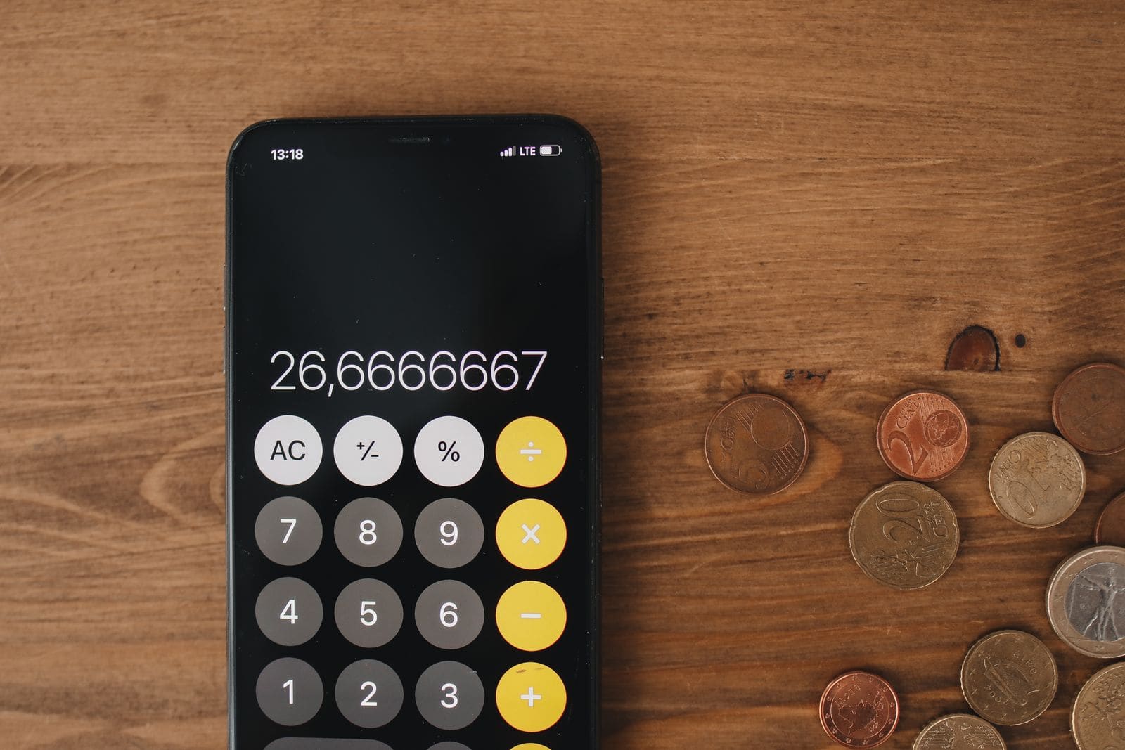 A calculator and coins on a wooden table